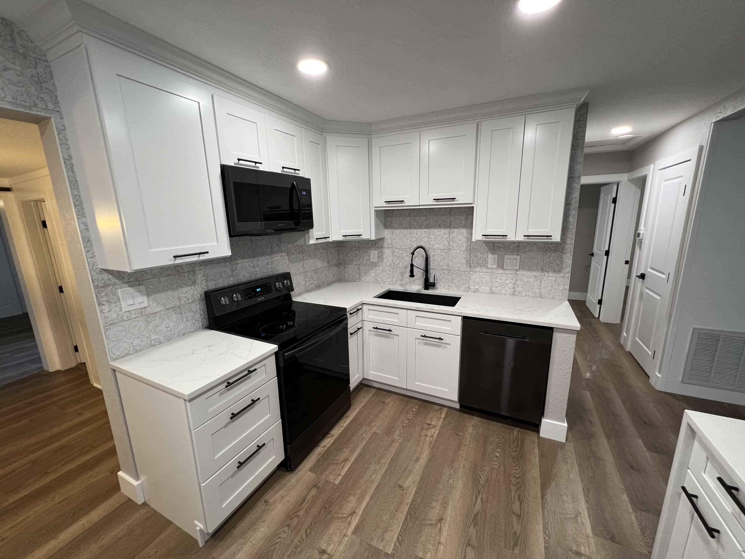 White kitchen with wood-look plank flooring installed by Crafted Kitchen and Bath